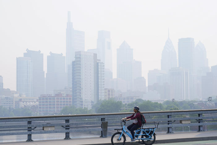 A person cycles past the skyline in Philadelphia shrouded in haze on Thursday.