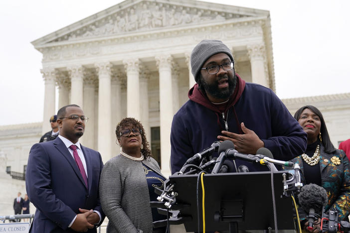 Evan Milligan, center, plaintiff in an Alabama redistricting case, speaks following Supreme Court oral arguments on Oct. 4, 2022. The court on Thursday ruled in favor of Milligan in the case, ordering the creation of a second Alabama congressional district with a large Black population.