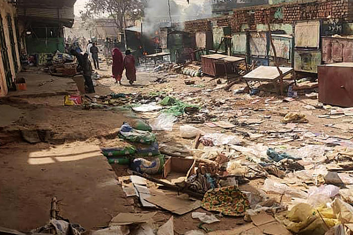 People walk among scattered objects in the market of El Geneina, the capital of West Darfur, as fighting continues in Sudan between the forces of two rival generals, on April 29, 2023.