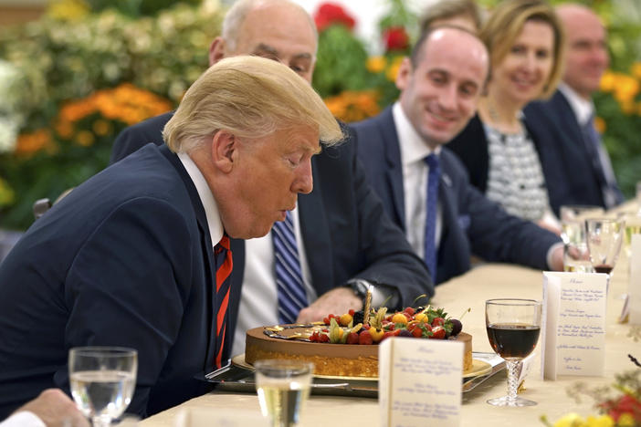 Then-President Donald Trump blows out a candle on a cake celebrating an early birthday during lunch with Singapore's Prime Minister Lee Hsien Loong on June 11, 2018.
