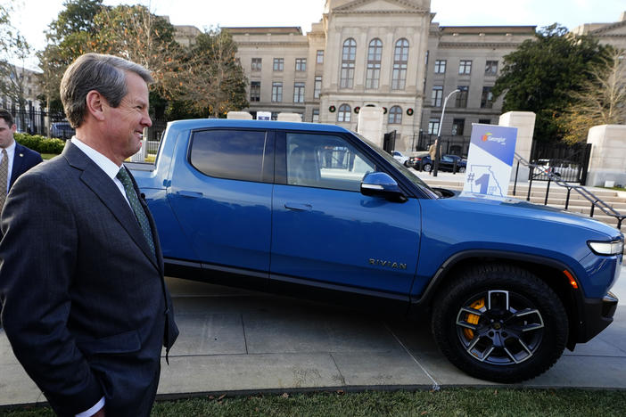 In Atlanta, Republican Gov. Brian Kemp stands next to a Rivian electric truck while announcing the company's plans to build a plant east of Atlanta, Dec. 16, 2021. Hyundai and Kia will also soon make electric vehicles in Georgia.