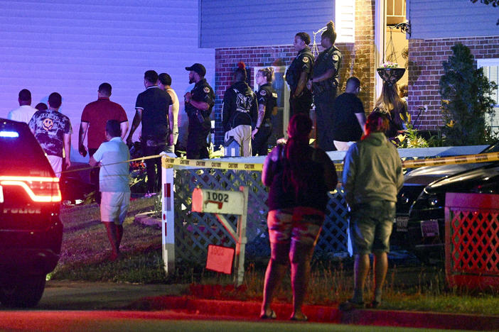 Police stand among a crowd outside a home where multiple people were shot in Annapolis, Md., on Sunday, June 11, 2023.