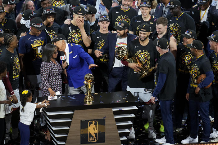 Denver Nuggets players, coaches and owners hold up the Larry O'Brien NBA Championship Trophy after the team's victory over the Miami Heat in Game 5 of basketball's NBA Finals, Monday, June 12, 2023, in Denver.