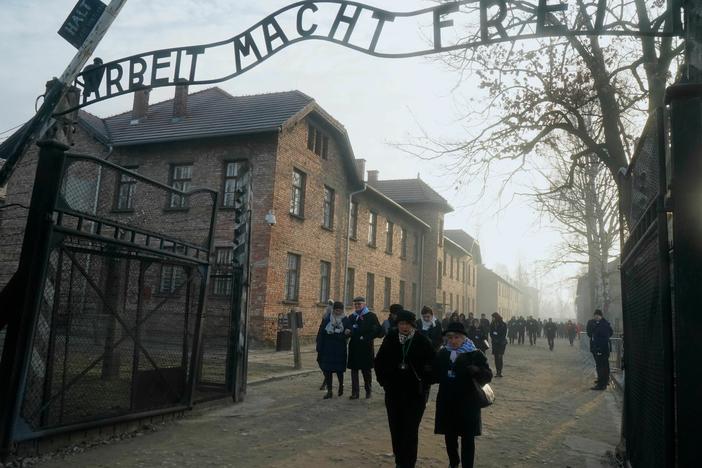 In this 2020 photo, survivors walk below a gate with the inscription "Work sets you free" after a wreath-laying ceremony at the memorial site of the former German Nazi death camp Auschwitz during ceremonies marking the 75th anniversary of the camp's liberation in Oswiecim, Poland.