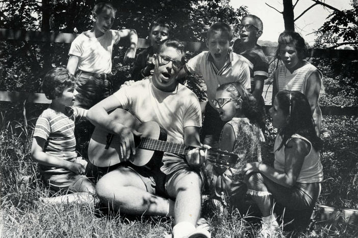 A camp counselor plays the guitar and leads children in singing at Camp Butwin in Minnesota in 1962.