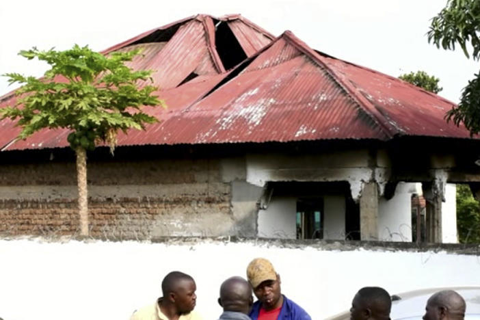 In this image made from video, people gather on Saturday in front of a building of the Lhubiriha Secondary School  Mpondwe, Uganda, near the border with Congo following an attack on the school.