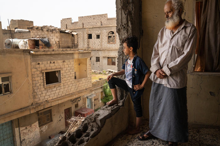 Abdullah Saif Ahmed Numan and his grandson, Mohammad, stand in the building where they live in Al Dawah neighborhood of Taiz, Yemen. The neighborhood is on the front line of a divided city in Yemen's civil war.