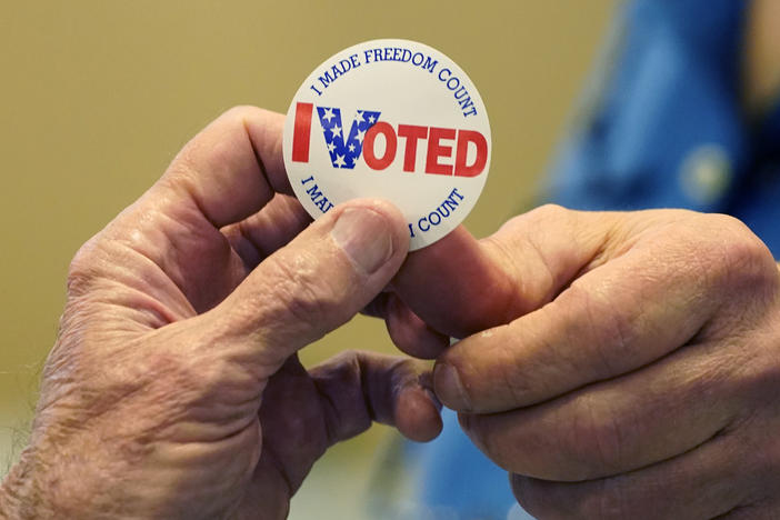 A poll worker in Brandon, Miss., right, hands an "I Voted" sticker to a person who filled out a ballot on Nov. 8, 2022.
