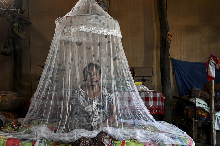 Francisca Sosa sits by her father, one of the many Peruvians who've contracted dengue fever in this unprecedented outbreak.