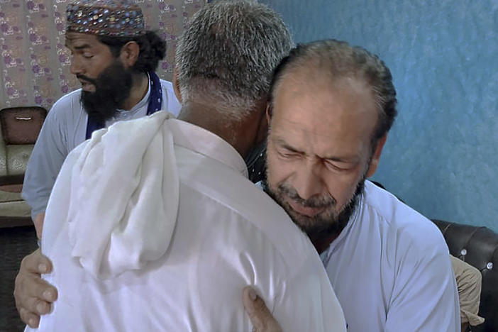 People offer their support to Raja Yousaf, right, whose son Raja Sajid is missing after a shipwreck off the Greek coast, in Bindian village in Kotli, a district of Pakistan's administrator Kashmir, Sunday, June 18, 2023.