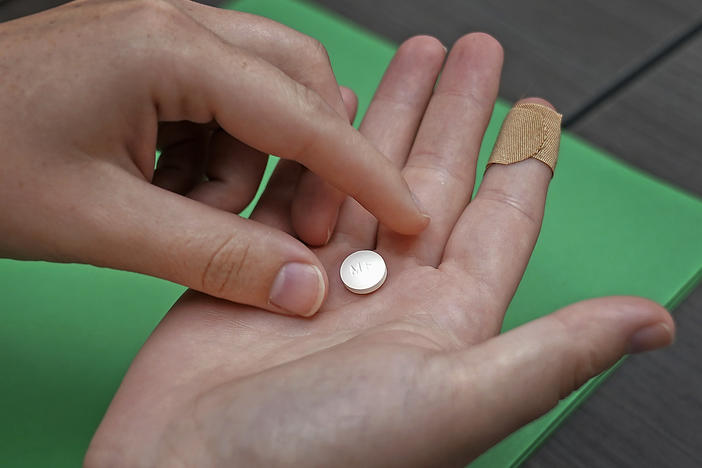 FILE - A patient prepares to take the first of two combination pills, mifepristone, for a medication abortion during a visit to a clinic in Kansas City, Kan., on Wednesday, Oct. 12, 2022.