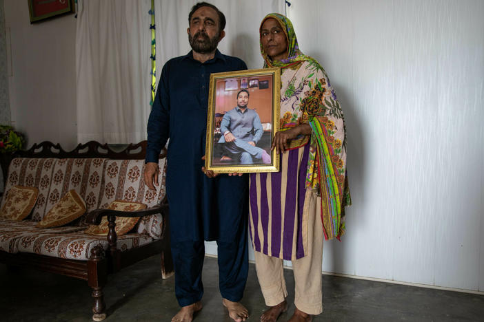 Syed Ali Raza and Rukhsana Jafri hold up a photograph of their son, Zain, who is missing after the migrant shipwreck. The family lives in Budho Kalas village, Punjab province, where Zain was a police officer. He had quit his job to start a business that wasn't profitable enough, then set off on an illegal migration to Europe for more lucrative employment.