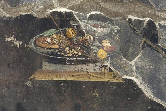 This picture provided on Tuesday, June 27, 2023, by the Pompeii Archaeological Park shows the wall of an ancient Pompeian house with a fresco depicting a table with food.