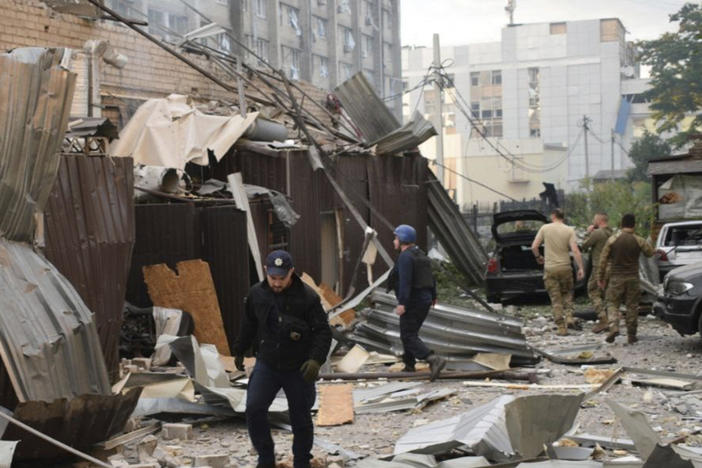 In this photo provided by the National Police of Ukraine, a police officer and a rescue worker walk in front of a restaurant RIA Pizza destroyed by a Russian attack in Kramatorsk, Ukraine, Tuesday, June 27, 2023.