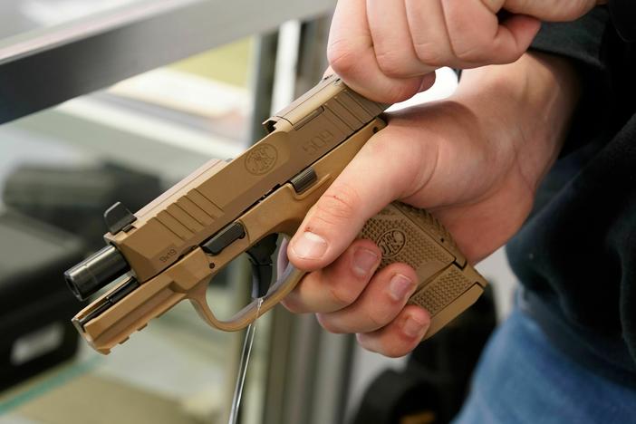 A worker clears a handgun for a customer at Davidson Defense in Orem, Utah, in 2021.