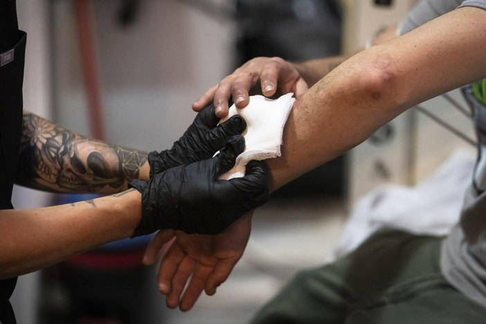 A nurse treats a man's skin wounds in a community outreach storefront in the Kensington neighborhood of Philadelphia in May. Xylazine, a powerful animal sedative that's moving through the illicit drug supply in the U.S., is causing gruesome skin wounds and scrambling longstanding methods for treating addiction and reversing overdoses.
