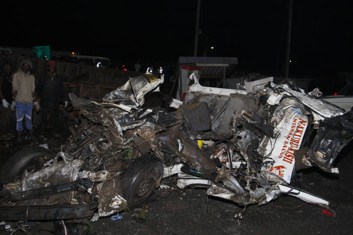 People stand near the wreckage of vehicles after a fatal accident in Londiani, Kenya, on Friday.