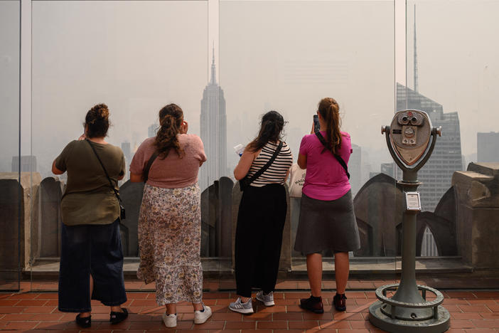 People at a viewing deck of the Rockefeller Center gaze at the Manhattan skyline on Friday during heavy smog brought by wildfire smoke from Canada.