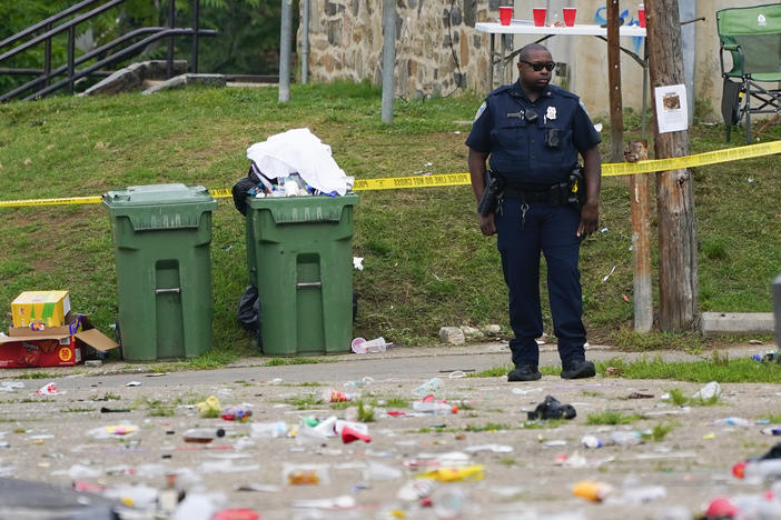 A police officer stands in the area of a mass shooting in the Southern District of Baltimore on Sunday.
