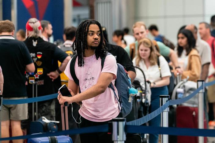 Travelers wait in line at Hartsfield-Jackson Atlanta International Airport in Atlanta on June 30, 2023, ahead of the 4th of July holiday weekend.  Consumers are traveling and eating out more though they are paring down spending in other ways.
