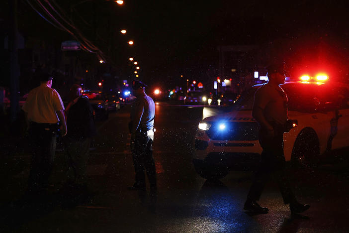 Philadelphia police stand at the intersection of 56th Street and Kingsessing Avenue after multiple people were shot in Southwest Philadelphia, late Monday, July 3, 2023.