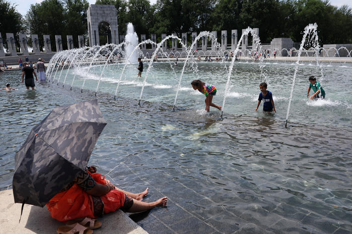 Visitors and tourists to the World War II Memorial in Washington, D.C., seek relief from the hot weather in the memorial's fountain on July 3. Due to extreme temperatures and high humidity, D.C. has declared a heat emergency, urging residents to take precautions outside and to stay hydrated.