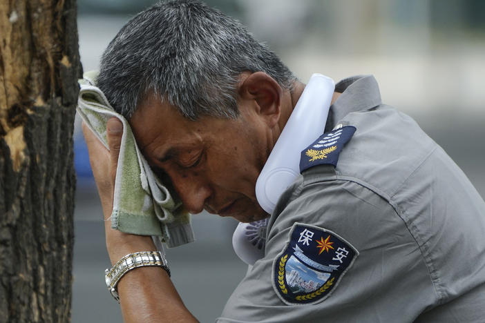 A security guard wipes sweat from his brow in Beijing, on July 3, 2023. Record-breaking heat is unfolding around the world because of human-caused climate change and the cyclic climate pattern El Niño.