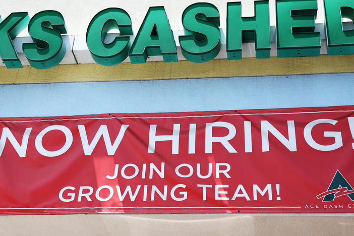 A 'Now Hiring' sign is displayed outside a check cashing shop in Los Angeles on June 2, 2023. Employers added 209,000 jobs last month, slowing down from previous months but still marking respectable growth.
