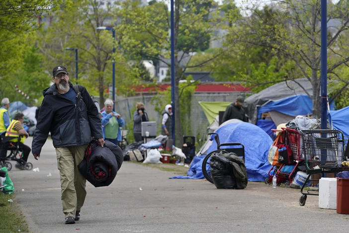 A man carries a sleeping bag at a homeless encampment in Portland, Maine, in May, before city workers arrived to clean the area. State officials say a lack of affordable housing is behind a sharp rise in chronic homelessness.