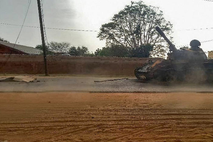 A covered body across from an armored vehicle on a street in the West Darfur state capital El Geneina on June 16, amid ongoing fighting between forces led by two generals in Sudan.