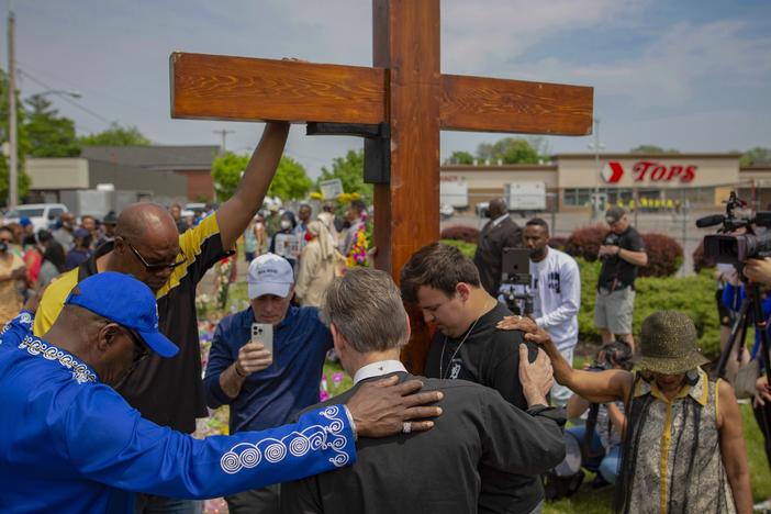 A new civil lawsuit filed Wednesday by families of the Buffalo Tops mass shooting victims targets a number of social media companies, gun retailers, a body armor manufacturer and the mass shooter's parents. Here, a group prays at the site of a memorial for the victims of the Buffalo supermarket shooting outside the Tops Friendly Market on Saturday, May 21, 2022, in Buffalo, N.Y.