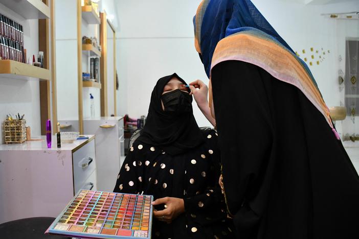 An Afghan beautician applies makeup to a client at a beauty salon in Mazar-i-Sharif.