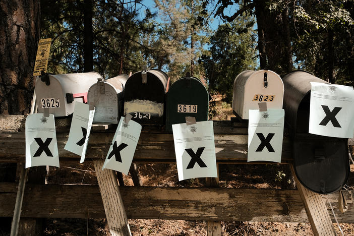 A row of mailboxes tagged with evacuation notices during the Oak Fire in Mariposa, Calif., in July 2022. Many residents in the area are losing their home insurance because of rising wildfire risk.