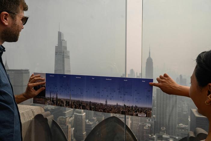 Heavy smoke from Canada's wildfires has put a thick haze over large parts of the U.S. this summer. Here, visitors to New York City hold a map showing city landmarks on a clear day as they stand on the viewing deck of Rockefeller Center in late June.