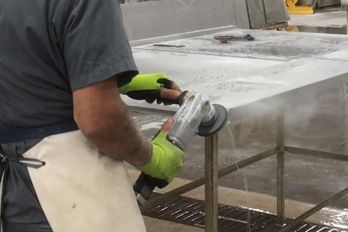 This image, from a video produced by government safety researchers, shows a countertop worker using a machine with a spray of water that's intended to control dust.