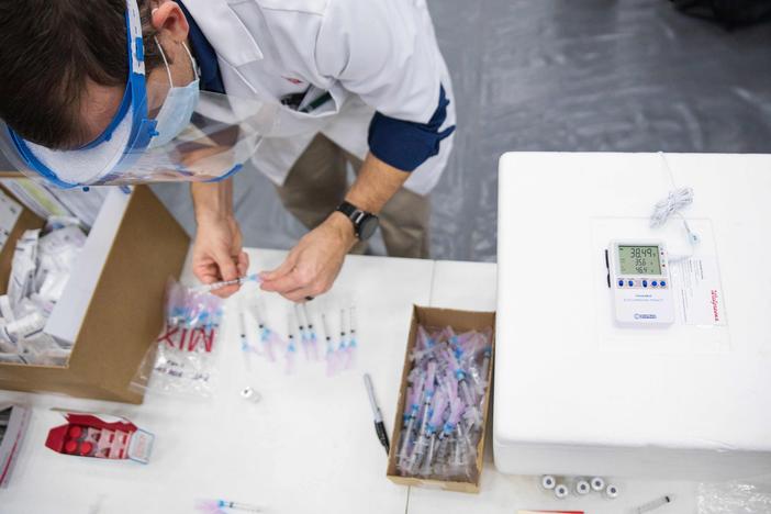 A new study finds a gap in excess deaths opened between Republicans and Democrats in 2021, after vaccine access was widened to all adults. Here, a Walgreens worker prepares vaccine shots for school staff in Dayton, Ohio, in February 2021.