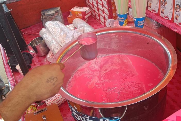 A vendor in Old Delhi mixes a pink beverage of Rooh Afza diluted with milk.