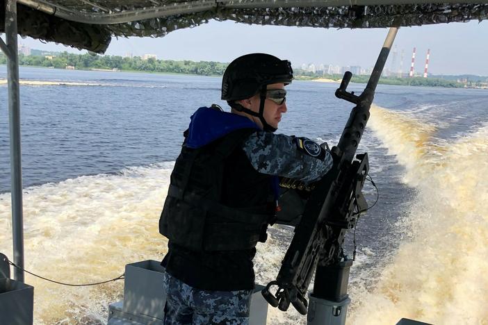 A Ukrainian sailor stands watch at a machine gun on the back of a patrol boat in the Dnipro River off Kyiv. Russia seized or destroyed much of Ukraine's navy, but the country is trying to rebuild its sea forces.
