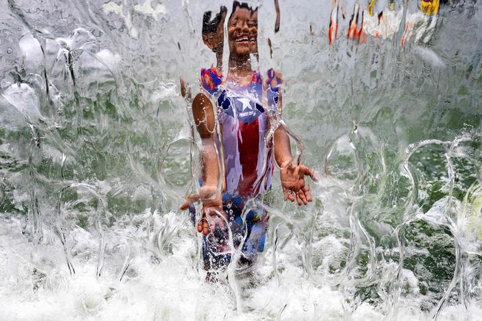 A summer of extreme heat is raising alarms of health risks. Here, a child plays in a waterfall feature at Yards Park in Washington, D.C., on June 26.