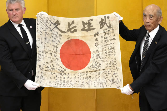 USS Lexington Museum executive director Steve Banta (left) and Toshihiro Mutsuda, the son of Japanese soldier Shigeyoshi Mutsuda, hold together the late soldier's "good luck flag" during a handover ceremony in Tokyo, on Saturday.