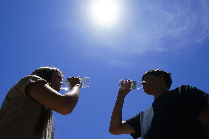 Tony Berastegui Jr., right, and his sister Giselle Berastegui drink water, Monday, July 17, 2023, in Phoenix. A historic heat wave that turned the Southwest into a blast furnace throughout July is beginning to abate with the late arrival of the monsoon rains.