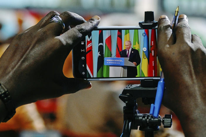 Russian President Vladimir Putin is seen on a phone screen as he attends a joint statement with President of Comoros Azali Assoumani at the Russia Africa Summit in St. Petersburg, Russia, Friday, July 28, 2023.
