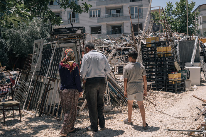 Emine, her husband and child search through materials recovered from destroyed buildings in Adiyaman.