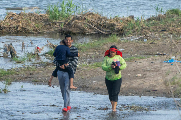 Migrants walk in the water along the Rio Grande border with Mexico in Eagle Pass, Texas.