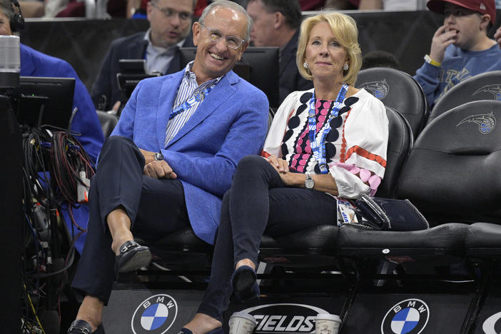 Dick DeVos (left) and former Secretary of Education Betsy DeVos watch from courtside seats during a game between the Orlando Magic and the Brooklyn Nets on March 26 in Orlando, Fla. The Magic is owned by the DeVos family.
