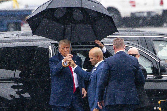 Donald Trump, left, is handed an umbrella from Walt Nauta, his personal aide and co-defendant in a felony case in Florida, on Thursday, the day the former president pleaded not guilty to four felony charges in Washington, D.C.