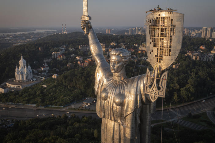 Workers install the Ukrainian coat of arms on the country's tallest statue, the Motherland Monument, after the Soviet coat of arms was removed, in Kyiv, Sunday. Ukraine is accelerating efforts to erase the vestiges of Soviet and Russian influence, pulling down monuments and renaming streets.