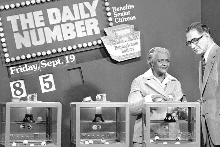 Pennsylvania citizen Mary Ann Gilliam, left, is aided by Pennsylvania Lottery district manager Peter H. Cardiges as she picks a number for a lottery drawing on Sept. 19, 1980 in Pittsburgh.