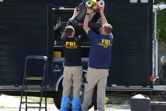 FBI officials unload the equipment as they process the home of Craig Robertson who was shot and killed by the FBI in a raid on his home this morning on August 9 in Provo, Utah.