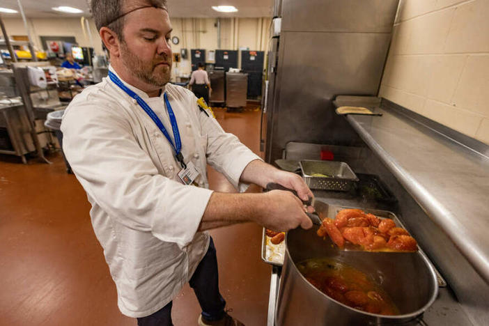Michael Hawley, general manager of the kitchen at Faulkner Hospital, places roasted tomatoes into a pot as he prepares the roasted tomato and shallot coulis.